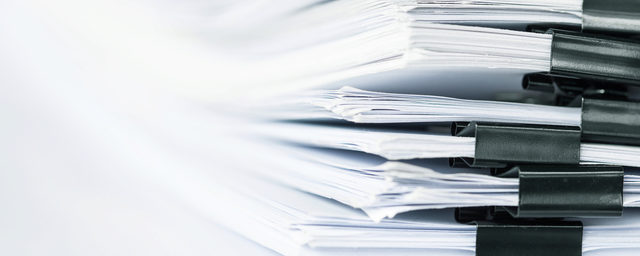 Image of papers organized and stacked together with binder clips